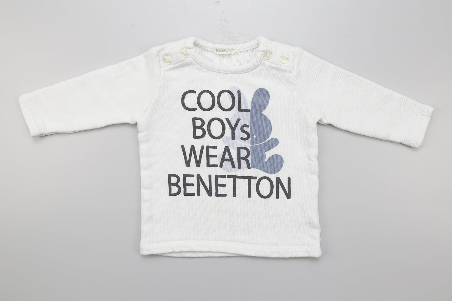 Weißer Jungenpullover mit Knöpfen an der Schulter.