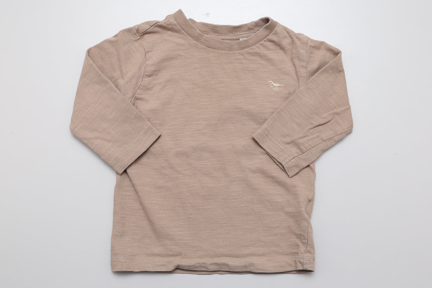 Sandfarbenes Langarmshirt mit kleinem gesticktem Dinosaurier auf der Vorderseite