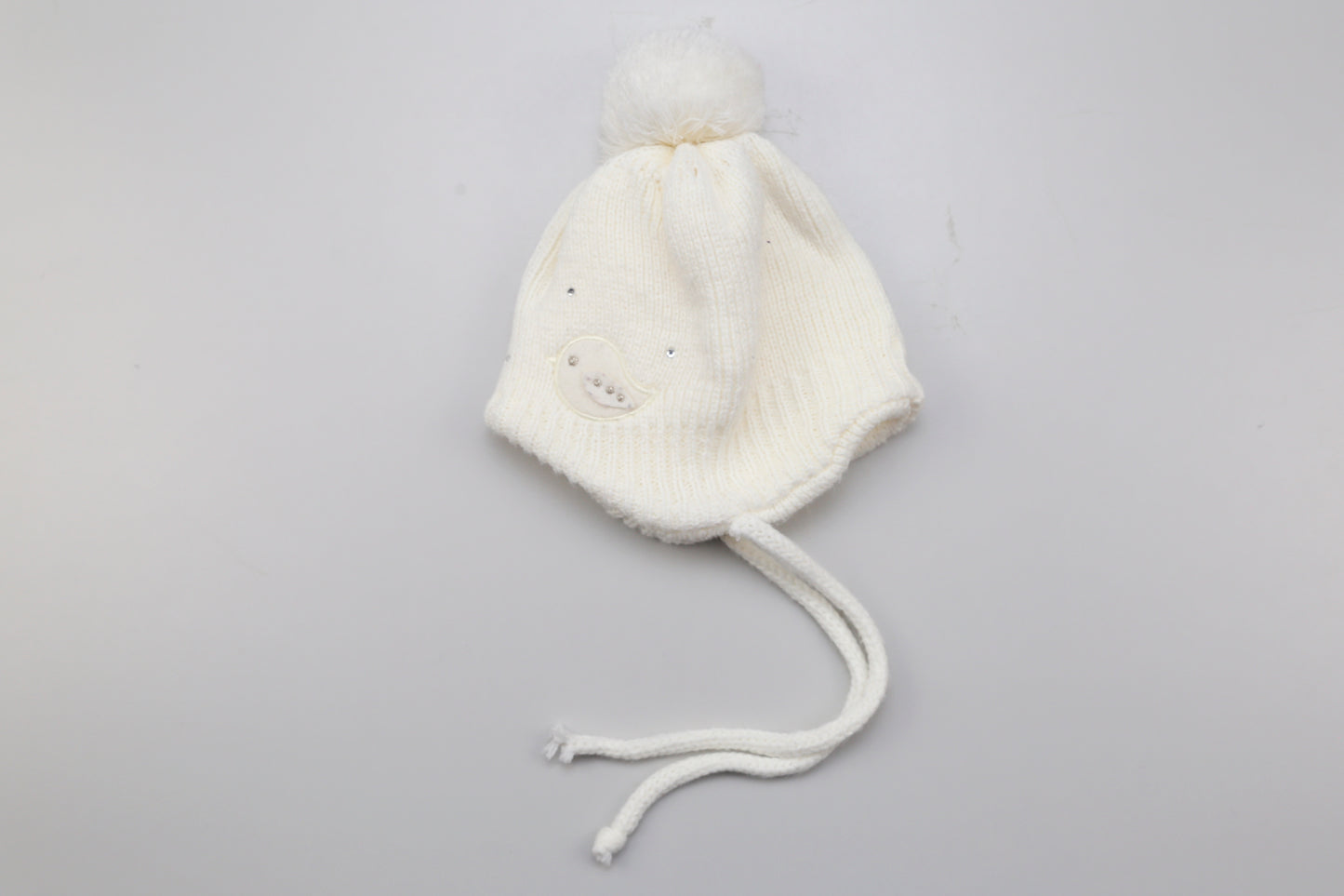 Weiße Mütze mit pompon und kleinen Vogelmotiven. 62