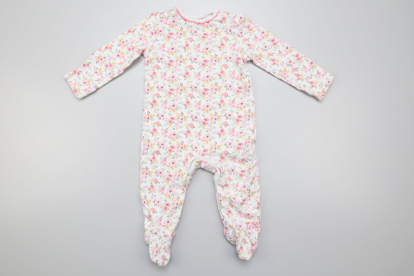 Kleine Blumen gemusterter Strampler aus Baumwolle mit umklappbaren Ärmeln. Unten mit Druckknöpfen. Zwei Druckknöpfe am Hals erleichtern das Ankleiden. 68