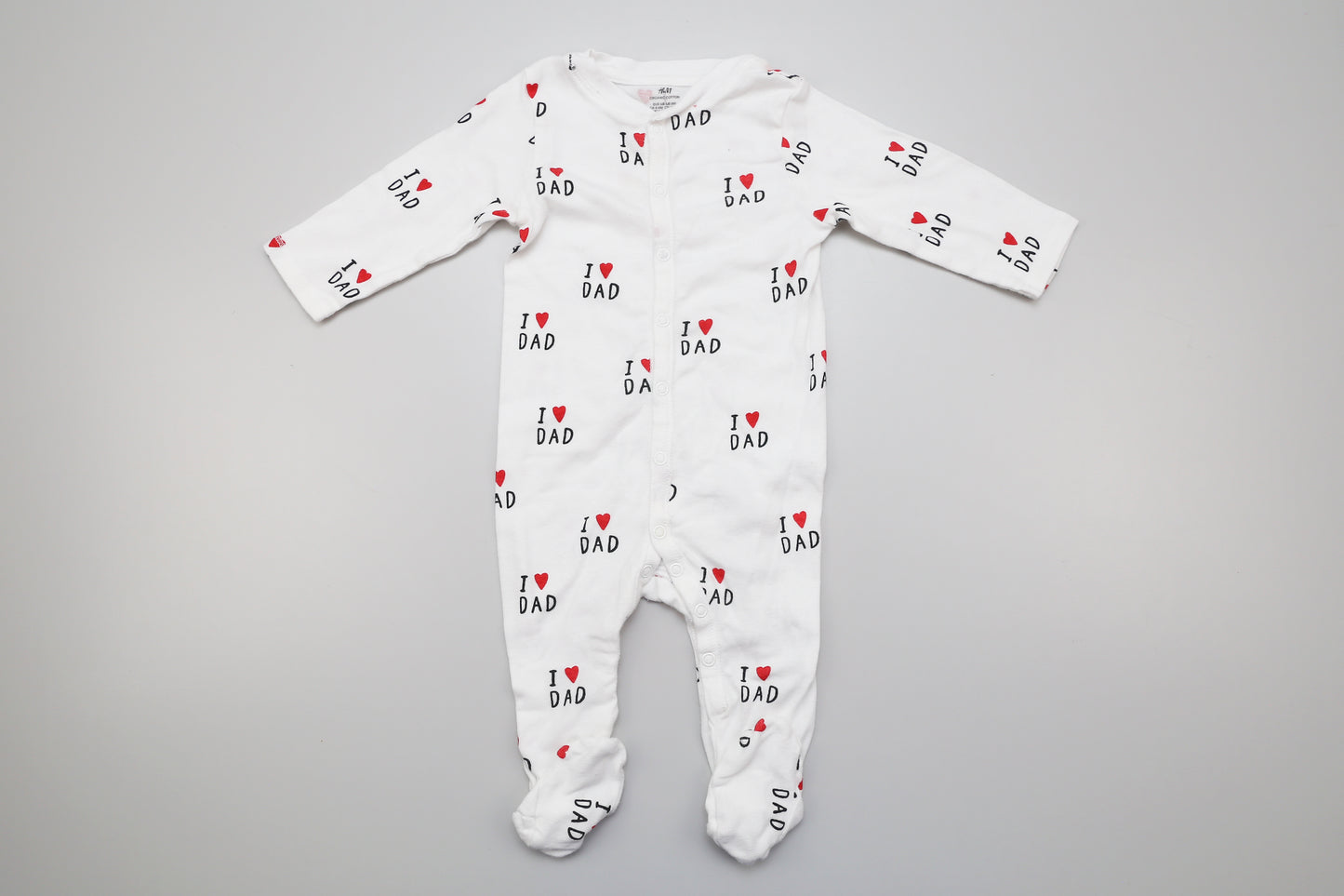 Weiße Bio-Baumwollstrampler mit "I love dad"-Aufdruck. Basierend auf der Größe entspricht er der Größe 68, ist jedoch länger als ein durchschnittlicher Strampler in dieser Größe.