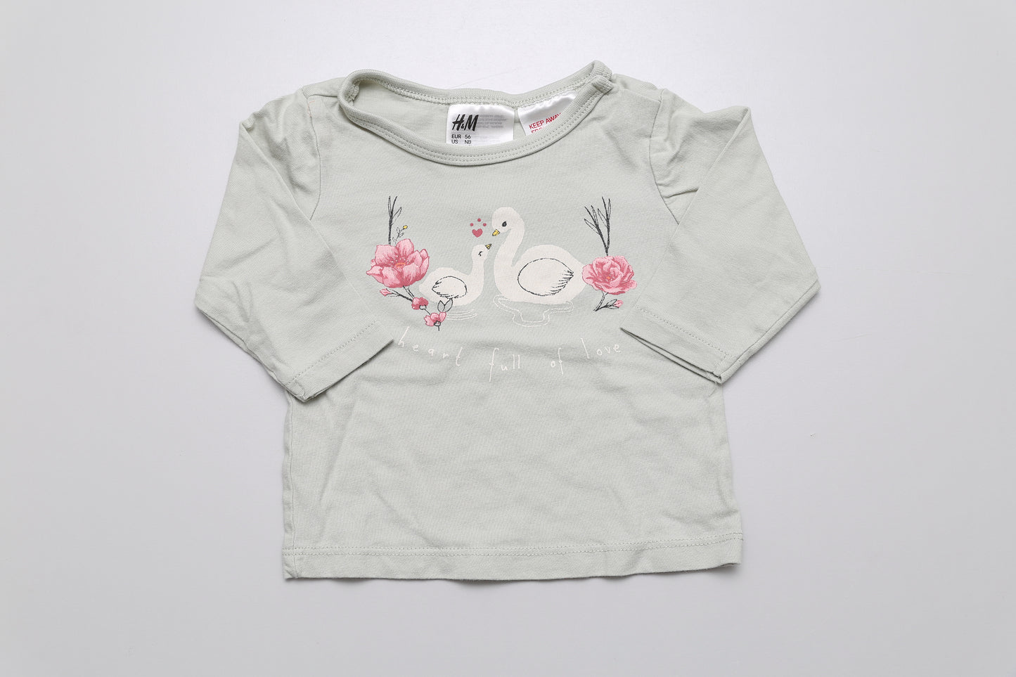 Hellgrünes langärmliges Baumwollshirt mit Schwanenmuster und Druckknöpfen an der Schulter. 56