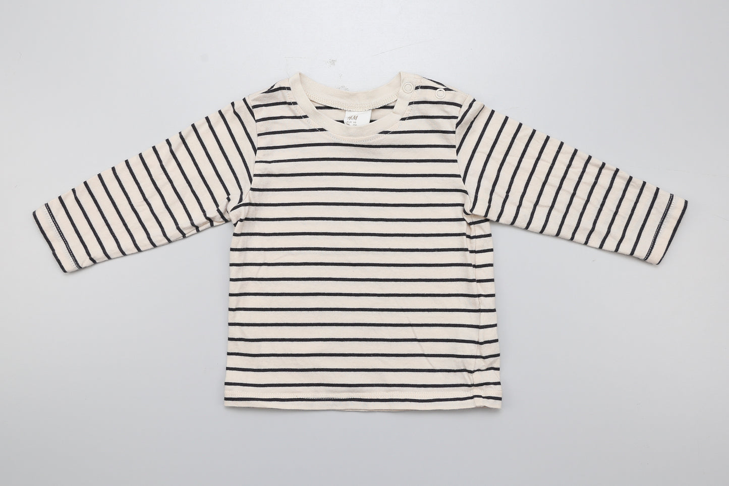 Schwarz-beiges Langarmshirt mit zwei Druckknöpfen am Hals.