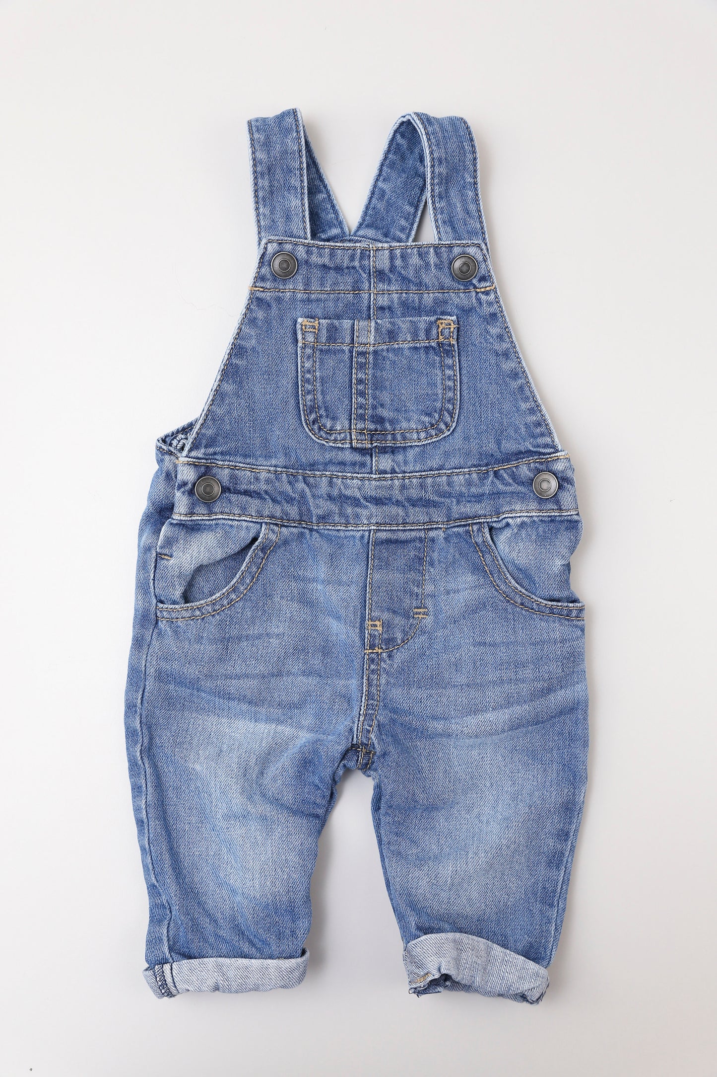 Latzhose für Jungen aus Jeansstoff mit Taschen. Zwei Druckknöpfe an den Trägern für längere Tragezeit. Im Schritt mit Druckknöpfen zu öffnen.