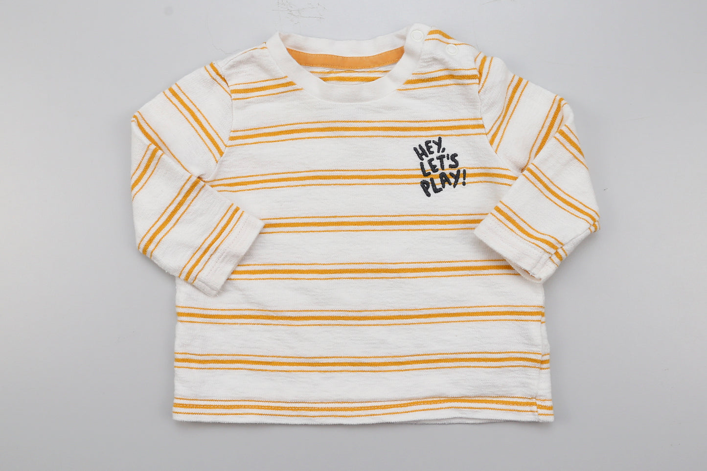 Gelbes gestreiftes Langarmshirt mit Aufdruck und zwei Druckknöpfen an der Schulter.