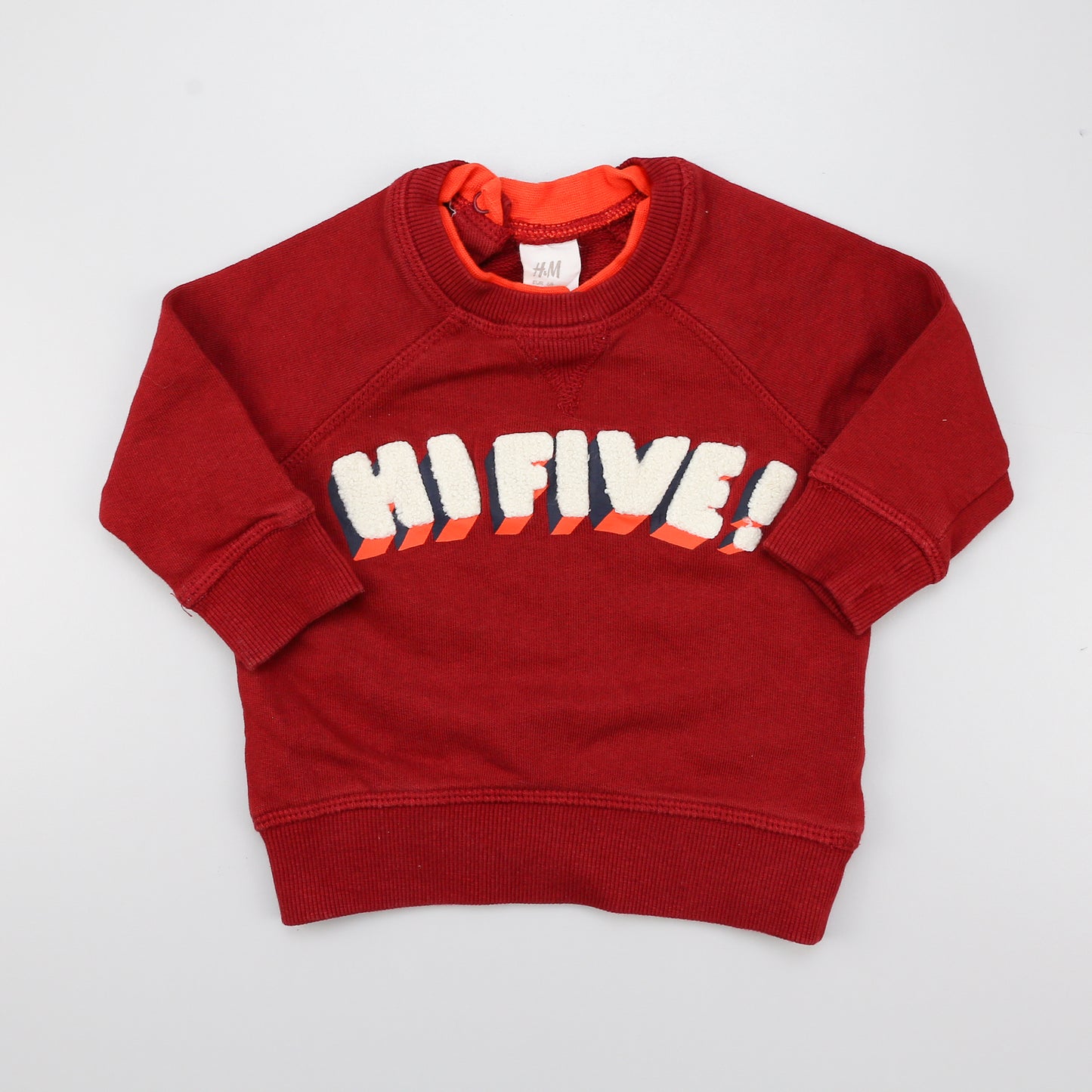 Roter Sweatpullover mit zwei Druckknöpfen hinten am Hals.