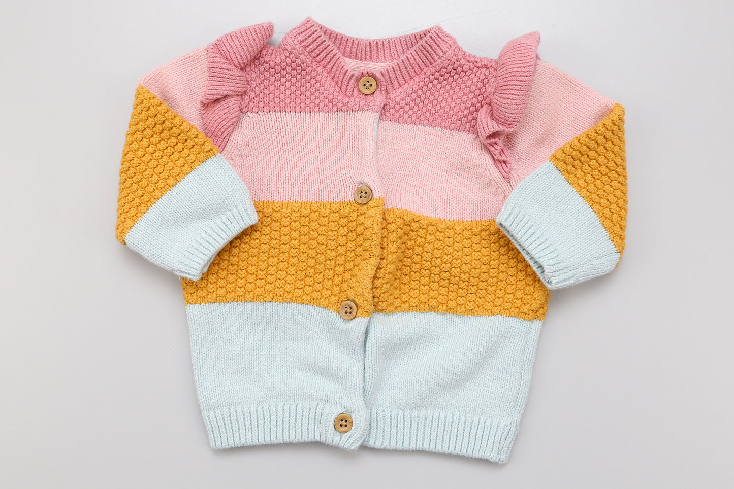 Rosa-gelber Strickcardigan mit Knöpfen vorne und Rüschen an den Schultern.