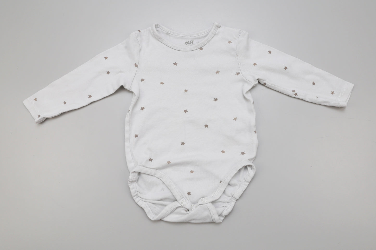Weißer Langarm-Babybody mit kleinen Sternen und Druckknopf am Halsausschnitt, Größe 74, leicht vergraut