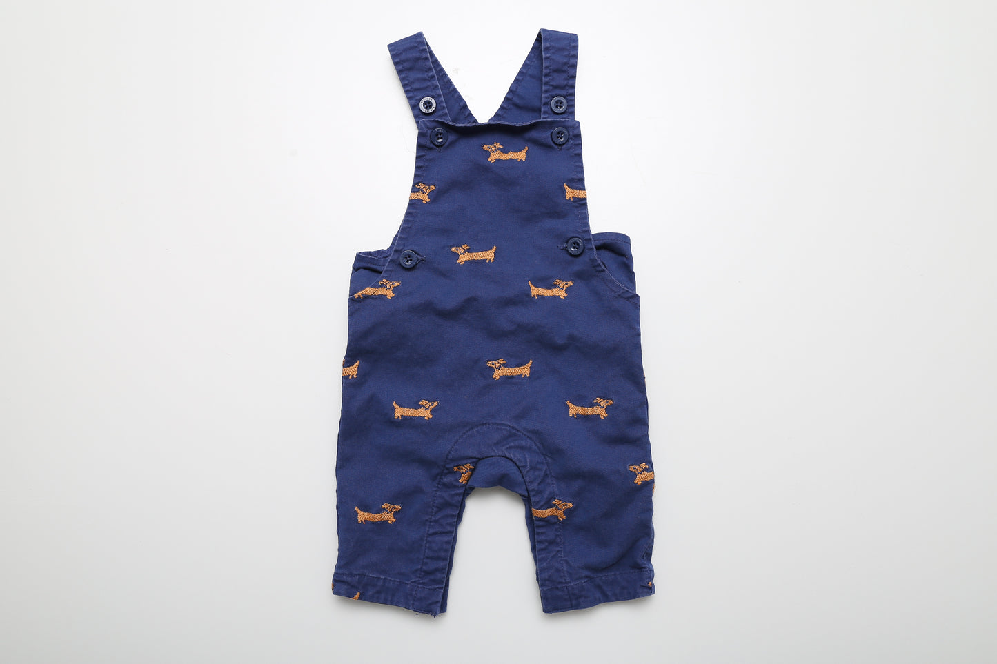 Blaue Latzhose mit süßem Hundemuster. Die Träger sind mit zwei Knöpfen verstellbar. In Größe 62 für Babys von 0-3 Monaten. Mit Druckknöpfen im Schritt.