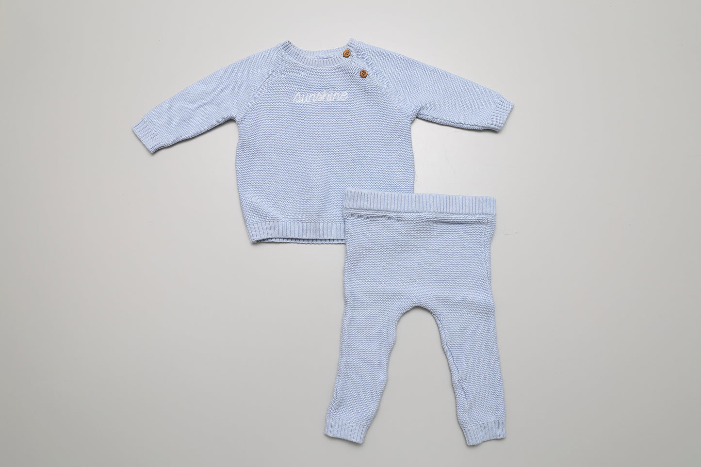 Weiches hellblaues Strickset aus Baumwolle mit „Sunshine“-Schriftzug. Größe 62, mit Knöpfen am Hals für bequemes Anziehen – perfekt für kleine Jungs.
