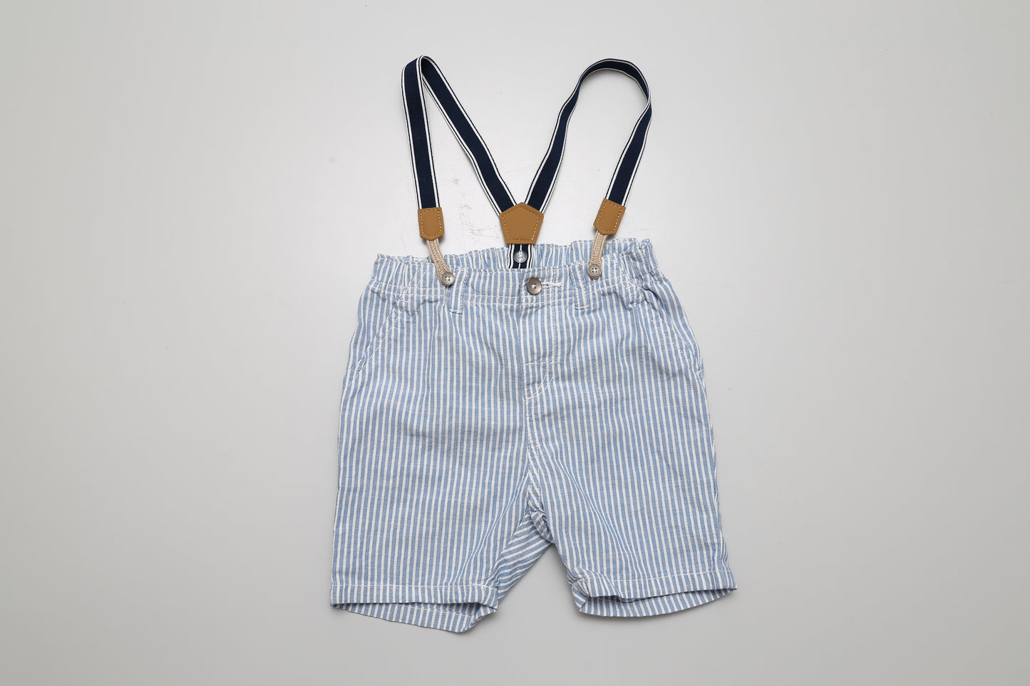 Blau-weiß gestreifte Shorts mit abknöpfbaren Trägern. Aus 100 % Baumwolle, Größe 92.