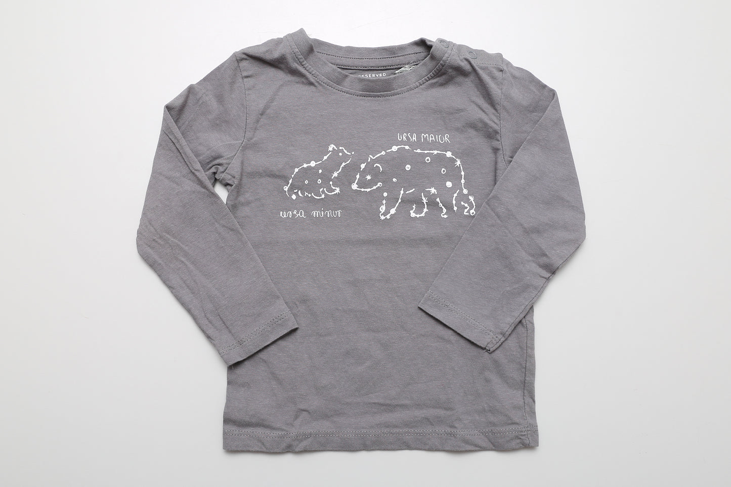 Graues Langarmshirt mit Sternbild-Motiv, an der Schulter mit Druckknöpfen. Aus 100 % Bio-Baumwolle, Größe 86.