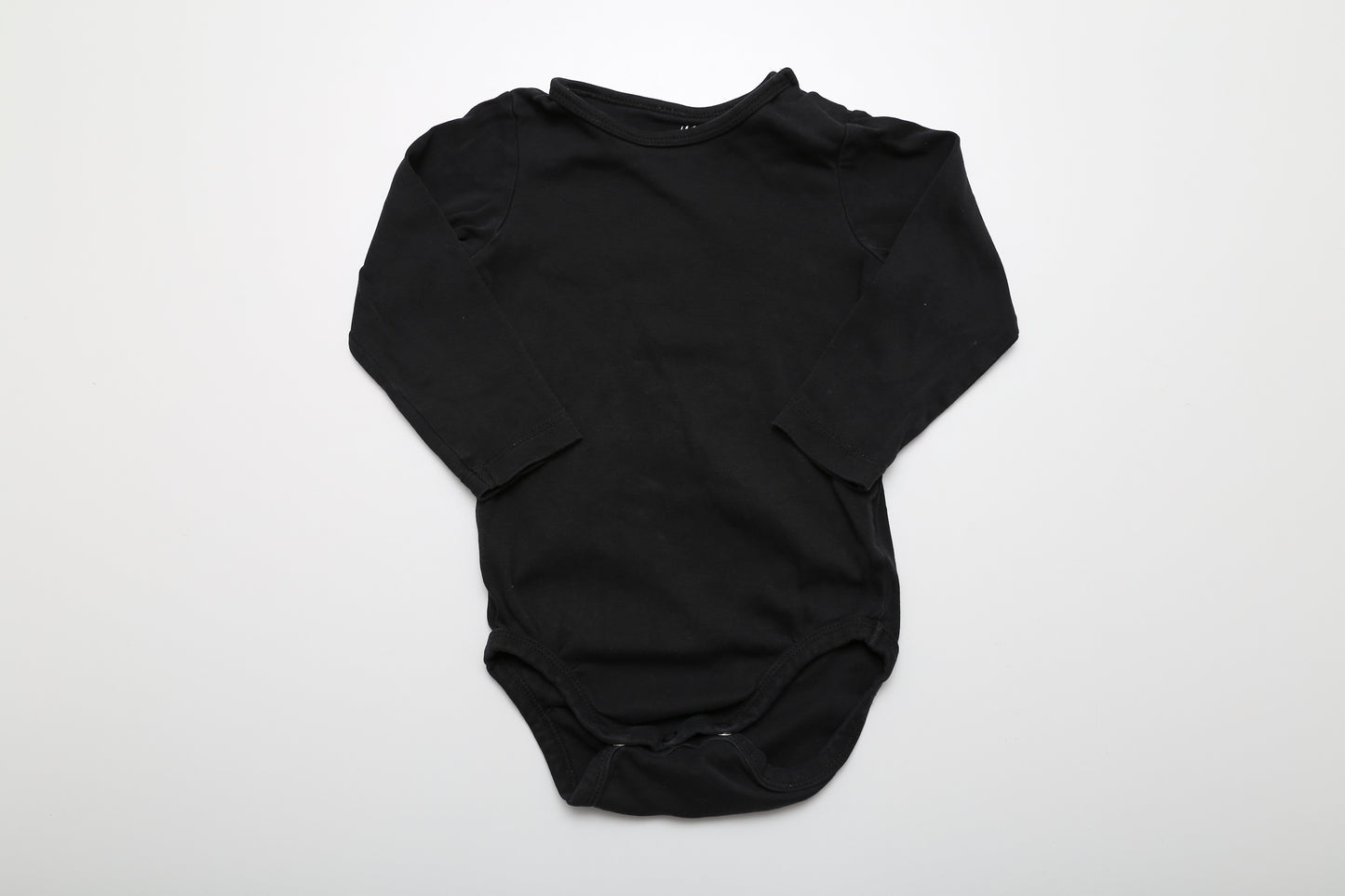 Schwarzer Langarm-Body aus Bio-Baumwolle, an der Schulter mit Druckknöpfen. Größe 86.