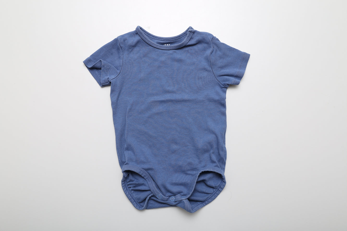 Dunkelblauer Kurzarm-Body aus Bio-Baumwolle. An der Schulter mit Druckknöpfen. Größe 86.