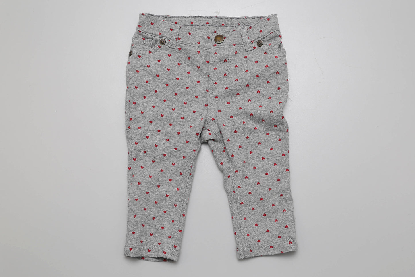 Graue Leggings mit roten Herzchen aus sehr dehnbarem Material, Größe 74-80. Laut Etikett für 6-12 Monate alte Babys geeignet.