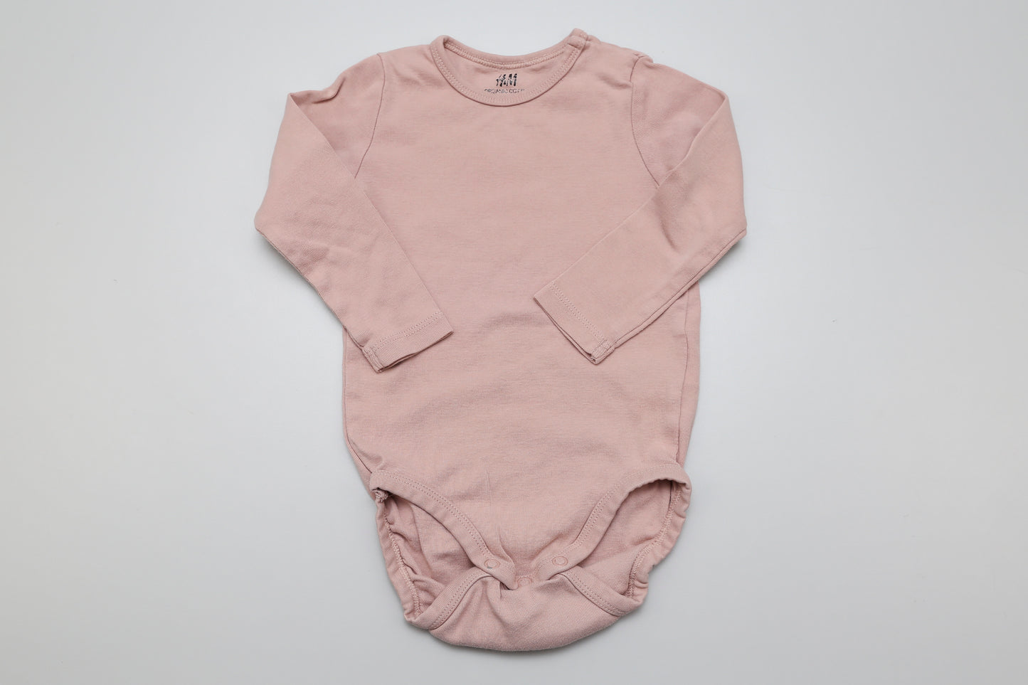 Zarter Langarm-Body in Rosatönen für kleine Mädchen – aus 100 % zertifizierter Bio-Baumwolle. Mit praktischen Druckknöpfen an der Schulter für einfaches Anziehen. Weich, bequem und perfekt für empfindliche Babyhaut. Passend in Größe 80.
