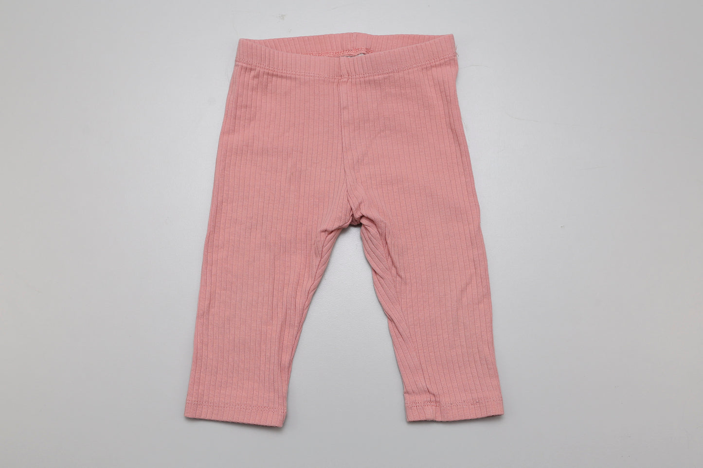 Leichte, rosa Baby-Leggings aus geripptem Material und 100 % Bio-Baumwolle – weich, dehnbar und hautfreundlich. Ideal für den Alltag oder als bequeme Schicht unter Kleidchen. Passend in Größe 74.