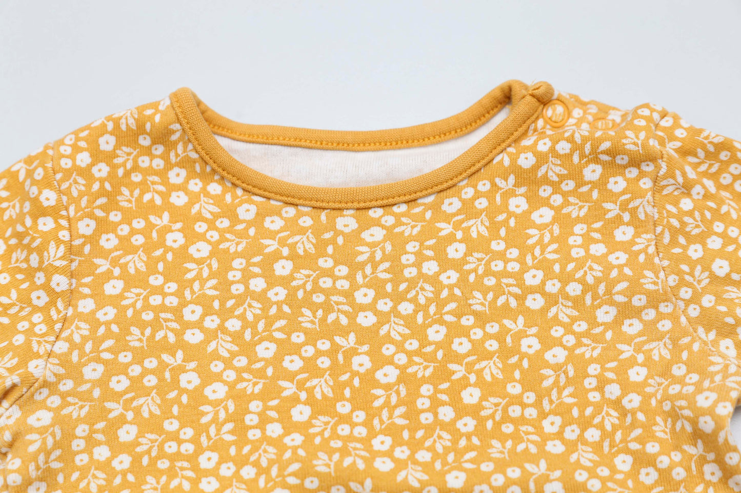 Gelbes Langarmshirt mit Blumenmuster und Schulterknöpfen (68-74)