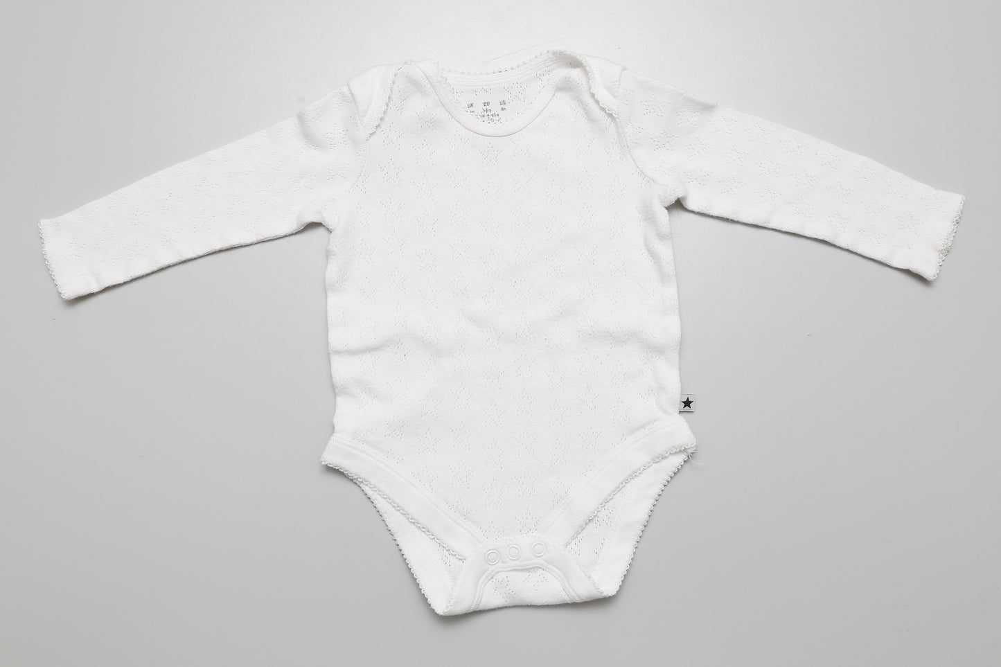 Weißer Langarm-Body für Mädchen mit strukturiertem Lochmuster in Größe 68.