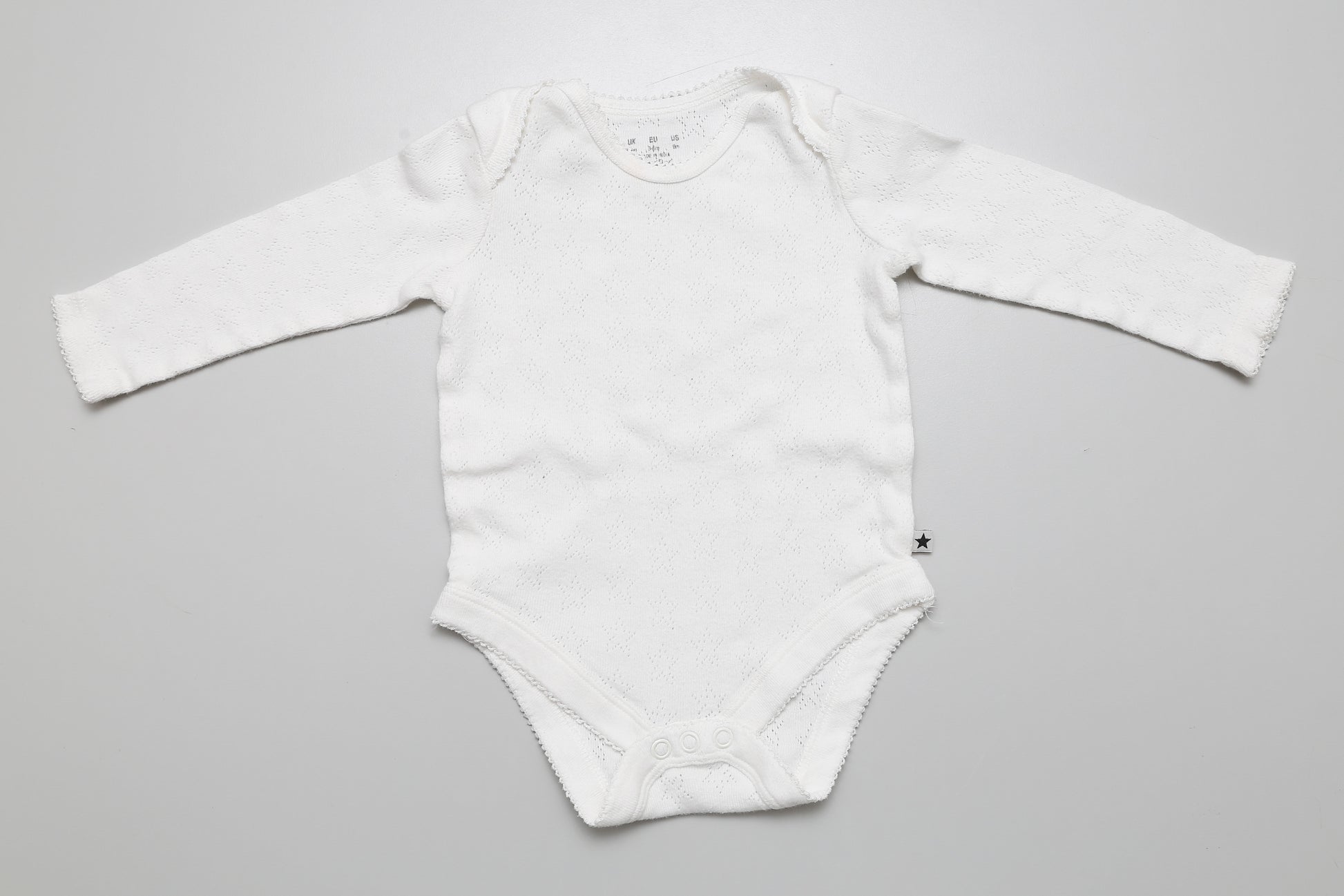 Weißer Langarm-Body für Mädchen mit strukturiertem Lochmuster in Größe 68.