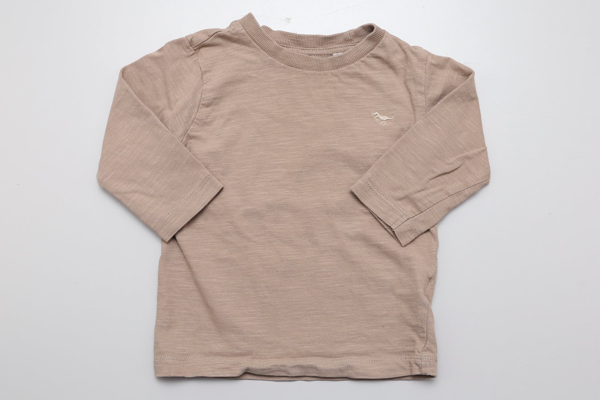 Sandfarbenes Langarmshirt mit kleinem gesticktem Dinosaurier auf der Vorderseite