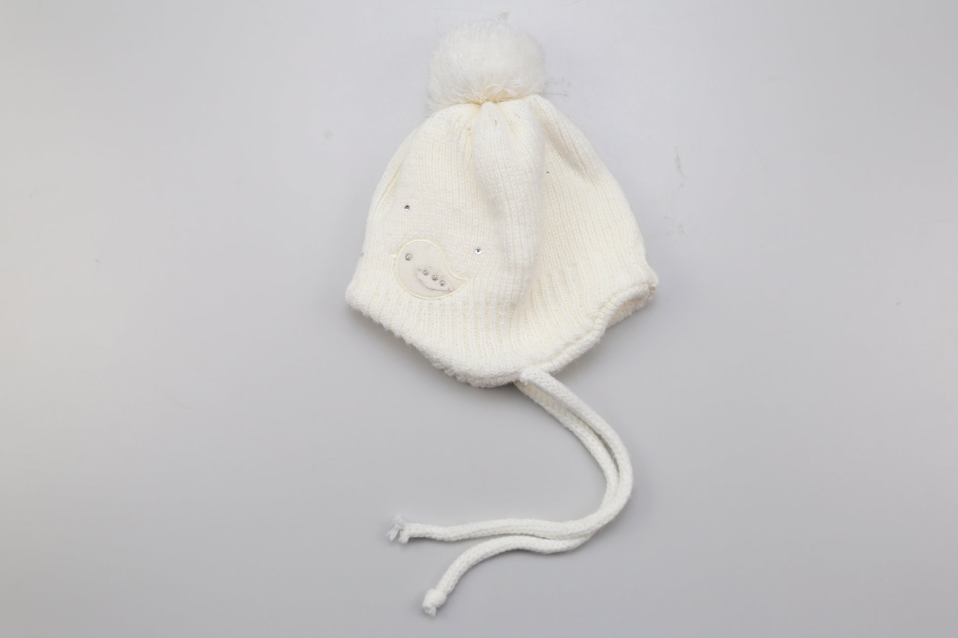 Weiße Mütze mit pompon und kleinen Vogelmotiven. 62