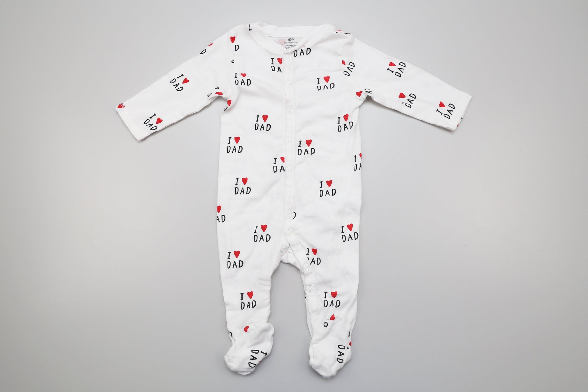 Weiße Bio-Baumwollstrampler mit "I love dad"-Aufdruck. Basierend auf der Größe entspricht er der Größe 68, ist jedoch länger als ein durchschnittlicher Strampler in dieser Größe.