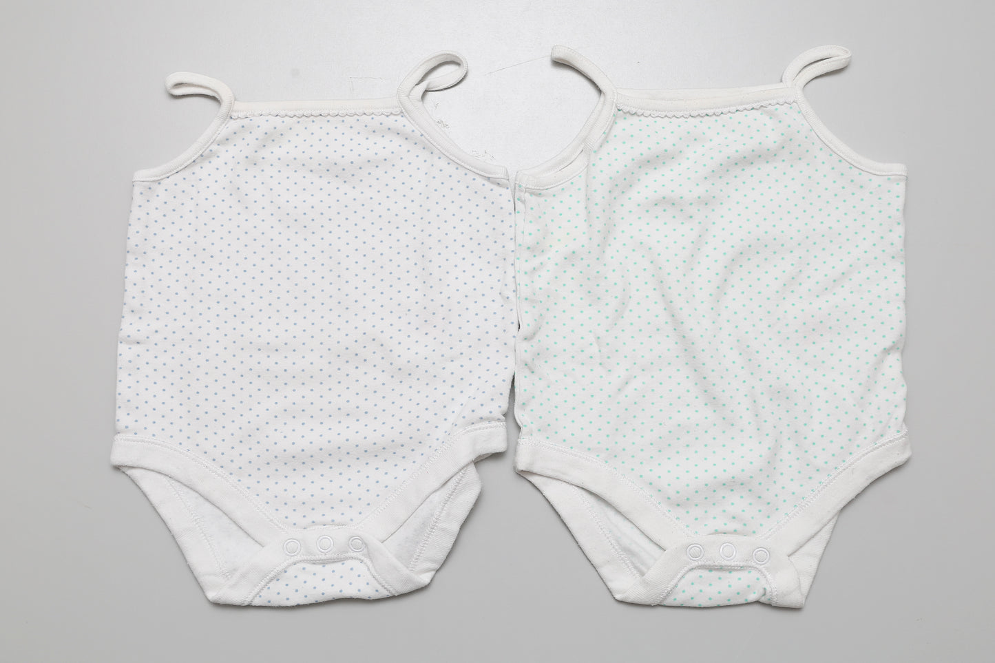 2-teiliges Set mit gepunkteten ärmellosen Bodys für Mädchen in Größe 74. Etwas kürzer und breiter geschnitten. Aus 100% Baumwolle.