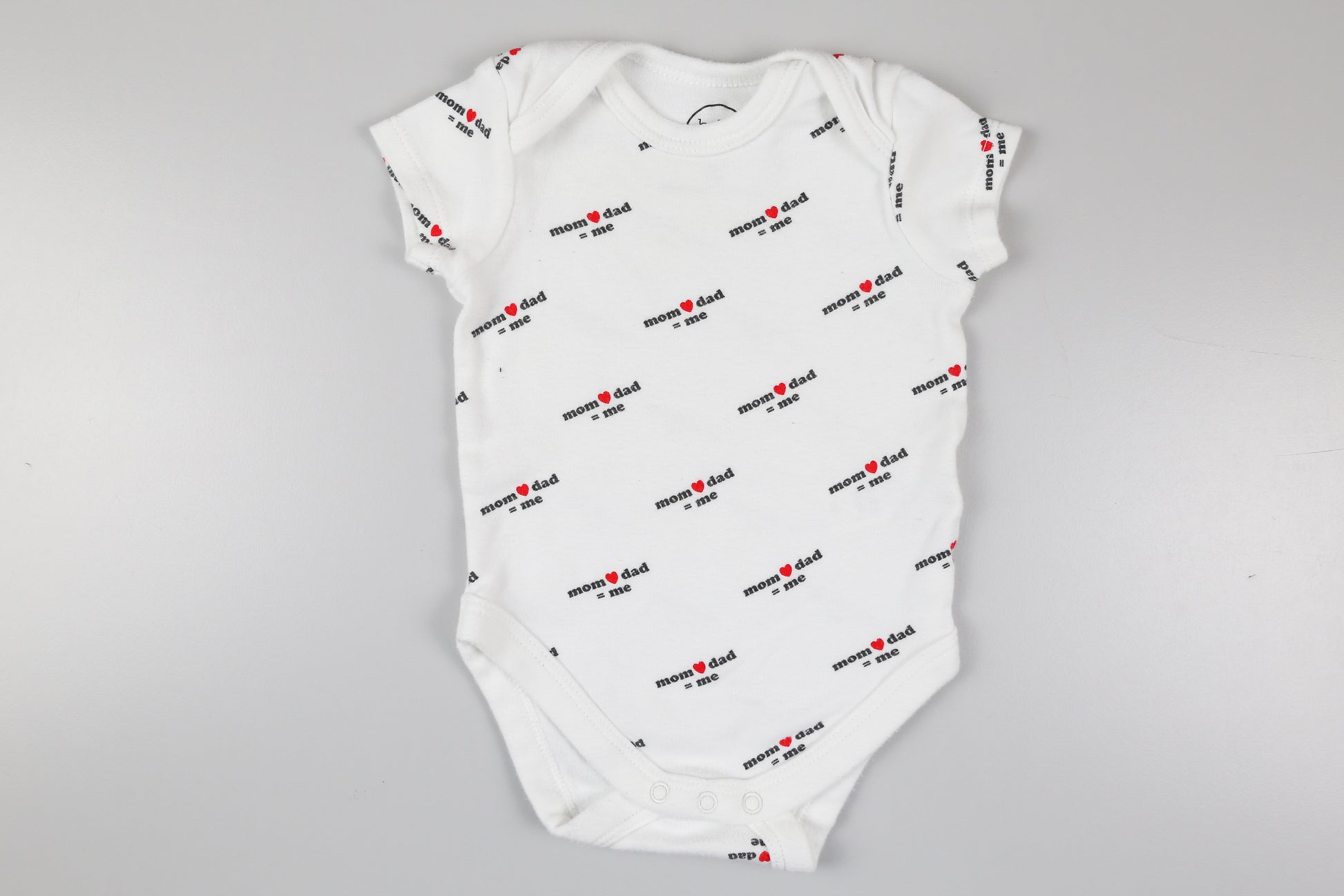 Weißer Kurzarmbody mit der Aufschrift ‚mom❤️dad=me’
