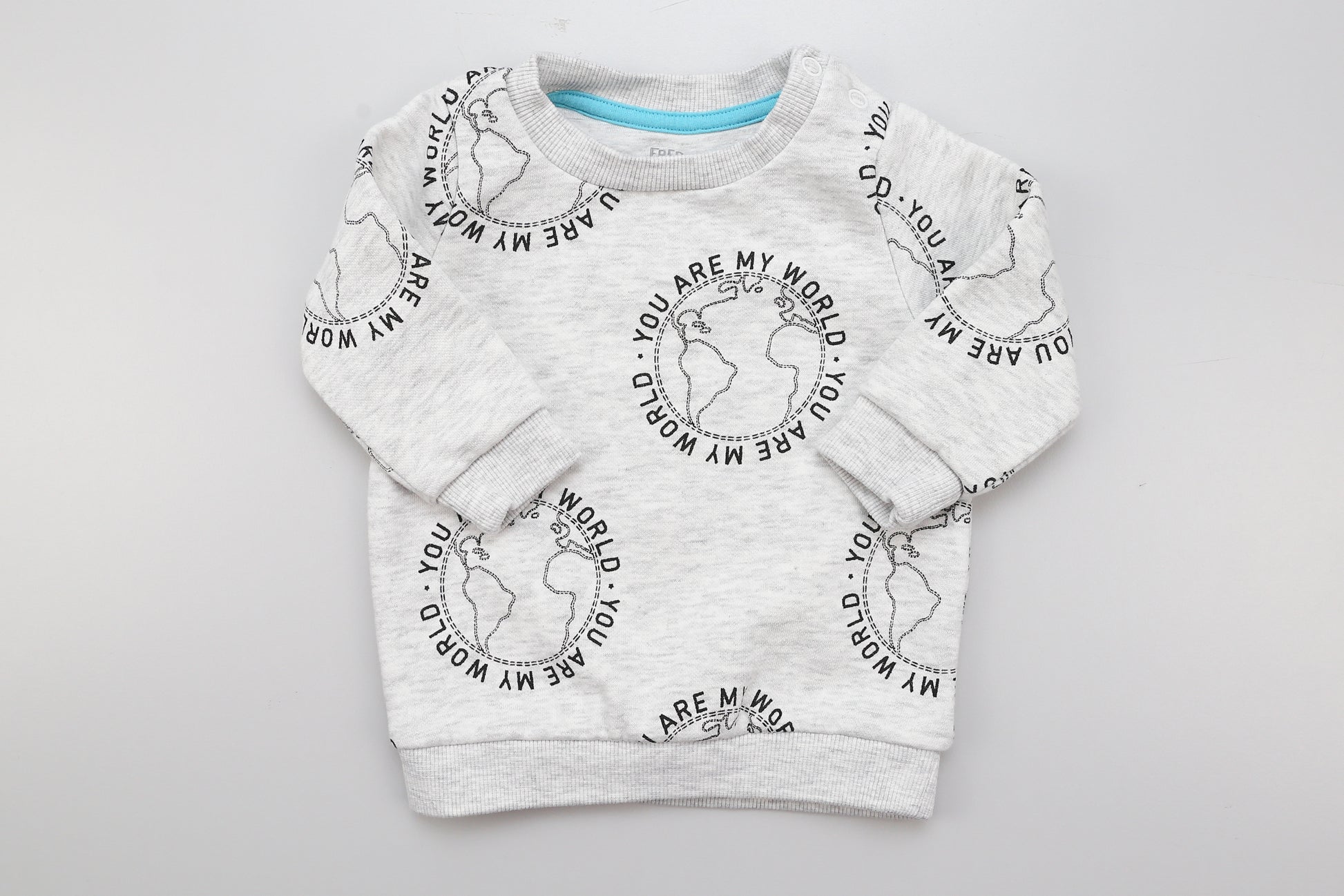 Helles graues Sweatshirt mit Aufdruck und zwei Druckknöpfen an der Schulter. Größe 56, fällt jedoch etwas größer aus.