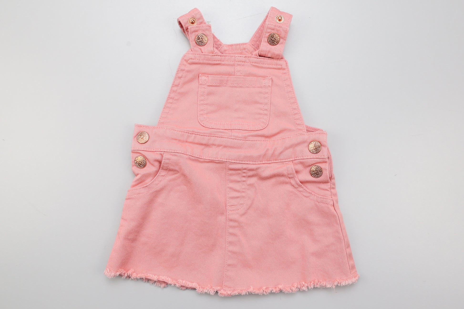 Rosa Latzjeanskleid mit verstellbaren Trägern und zwei Druckknöpfen.