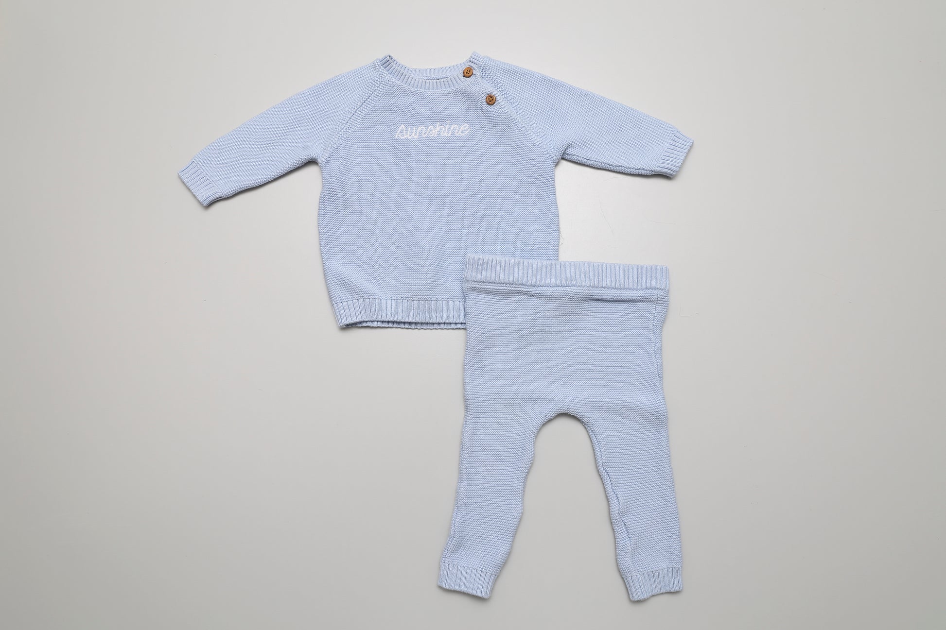 Weiches hellblaues Strickset aus Baumwolle mit „Sunshine“-Schriftzug. Größe 62, mit Knöpfen am Hals für bequemes Anziehen – perfekt für kleine Jungs.