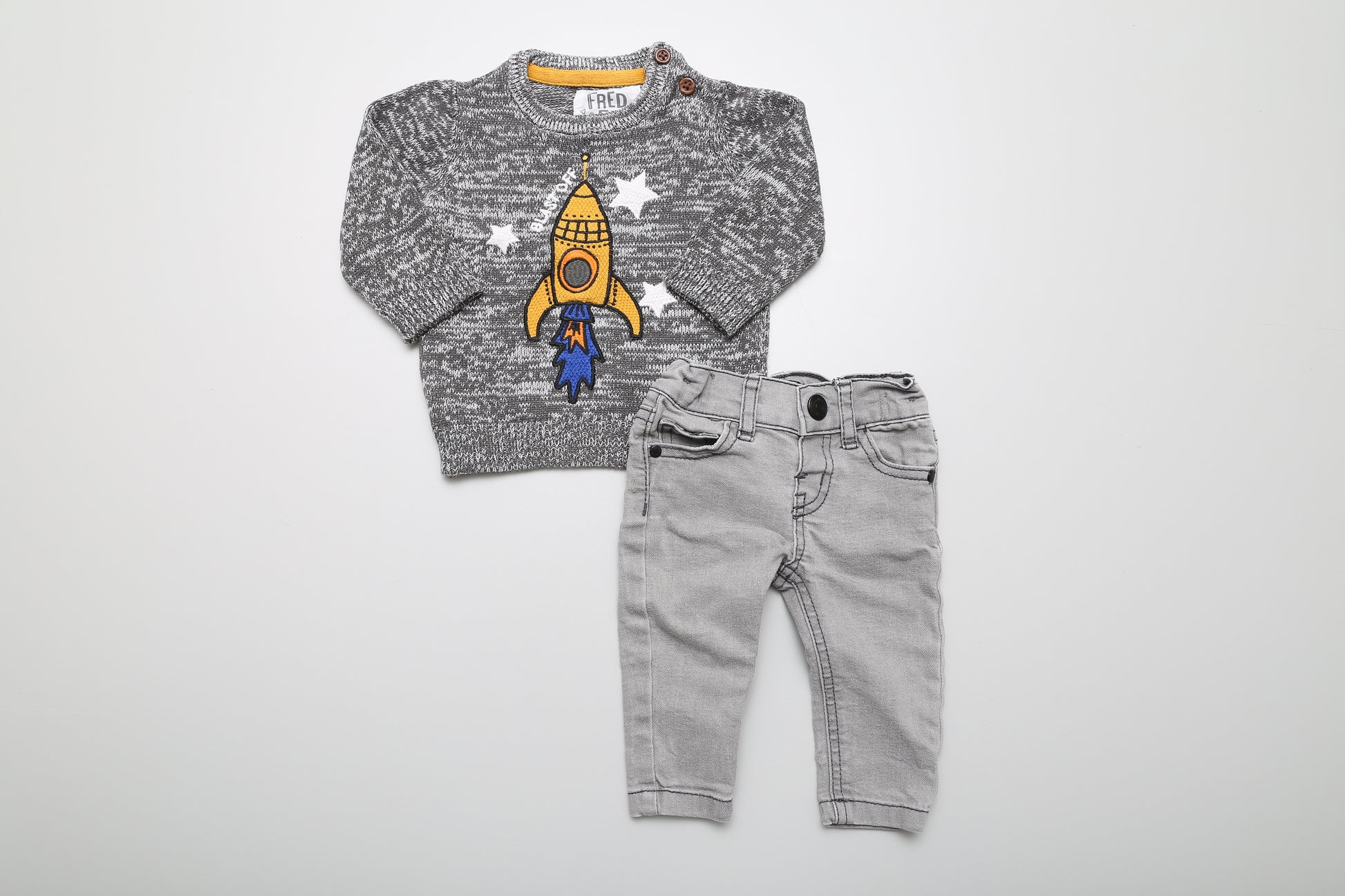 Süßes graues Astronauten-Set in Größe 62. Der Fred&amp;Flo Baumwollpullover hat Knöpfe am Halsausschnitt für einfaches Anziehen. Die Denim-Jeans hat einen verstellbaren Bund und Druckknöpfe.
