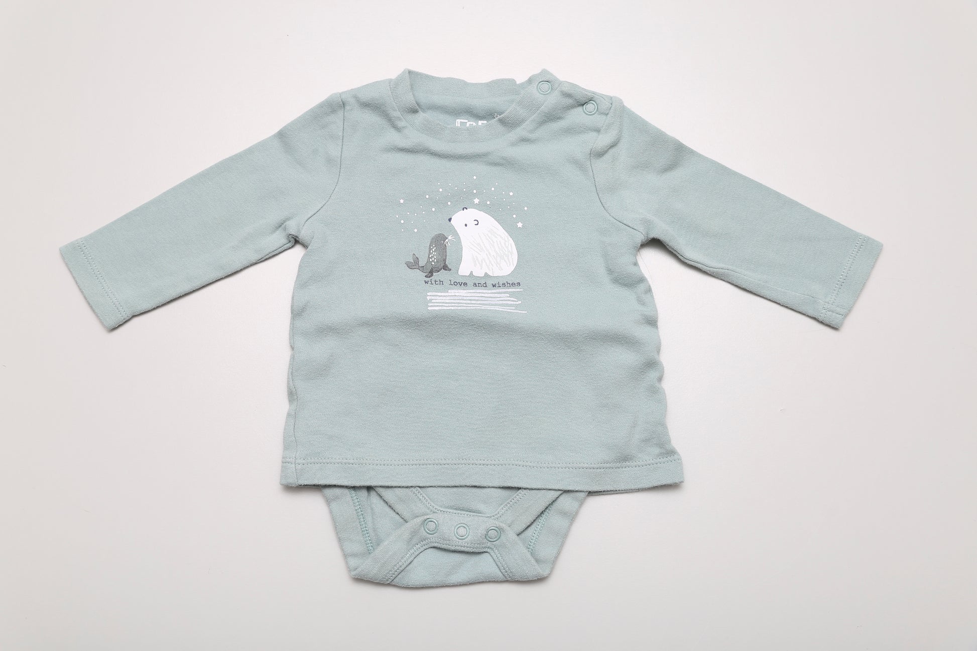 Hellgrünes T-Shirt-Body mit Eisbärenmotiv. Am Halsausschnitt mit Druckknöpfen zu öffnen. 100 % Baumwolle, Größe 62. Minimal waschpilling vorhanden.