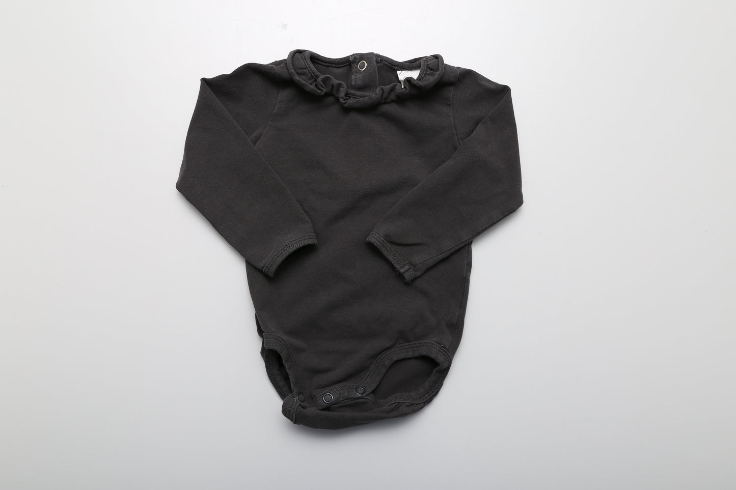 Schwarzer Langarm-Body mit Rüschen am Hals und Druckknöpfen am Rücken für einfaches Anziehen, in Größe 74.