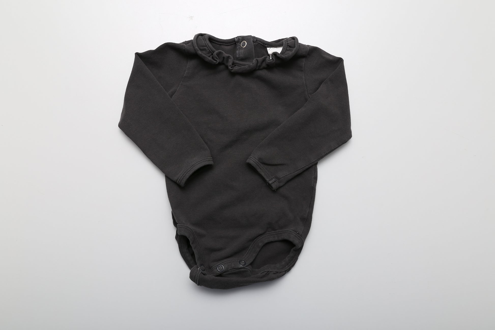 Schwarzer Langarm-Body mit Rüschen am Hals und Druckknöpfen am Rücken für einfaches Anziehen, in Größe 74.