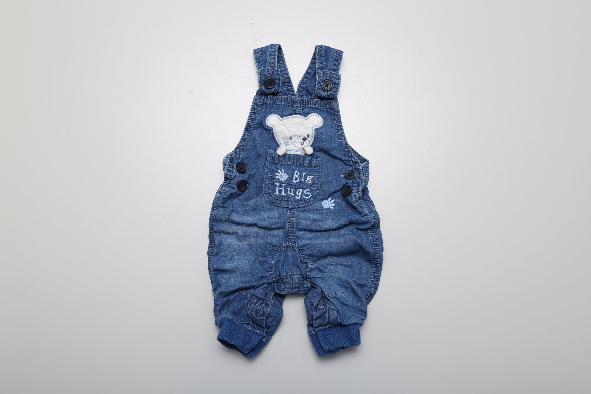 Latzhose aus Jeansstoff mit Bärenmotiv. Unten mit Druckknöpfen zu öffnen. Größe 50-56.