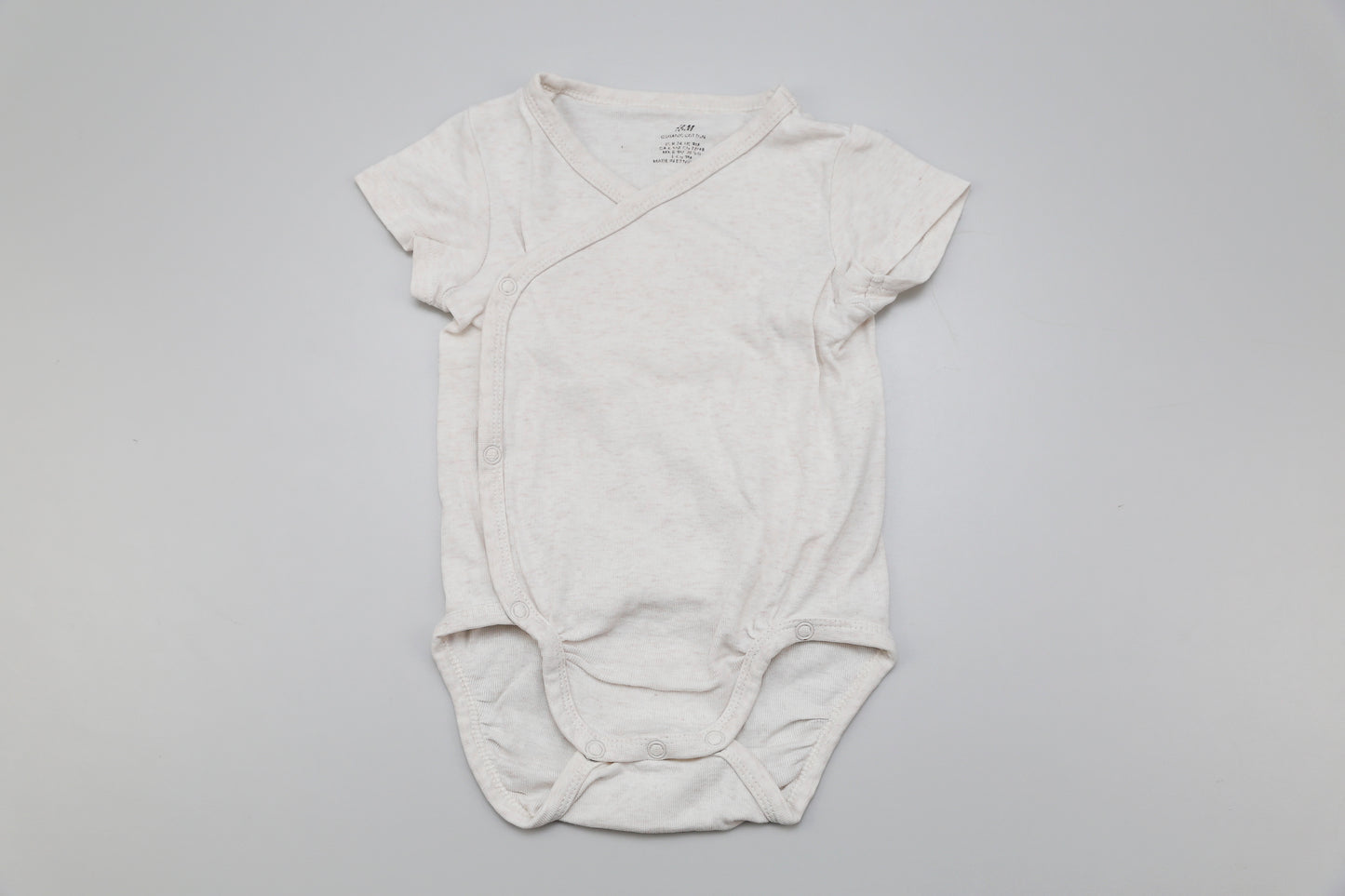 Zeitloser Wickelbody mit kurzen Ärmeln in neutralem Beige – aus 100% Bio-Baumwolle. Für Mädchen und Jungen geeignet. Größe 74, weich, bequem und nachhaltig.