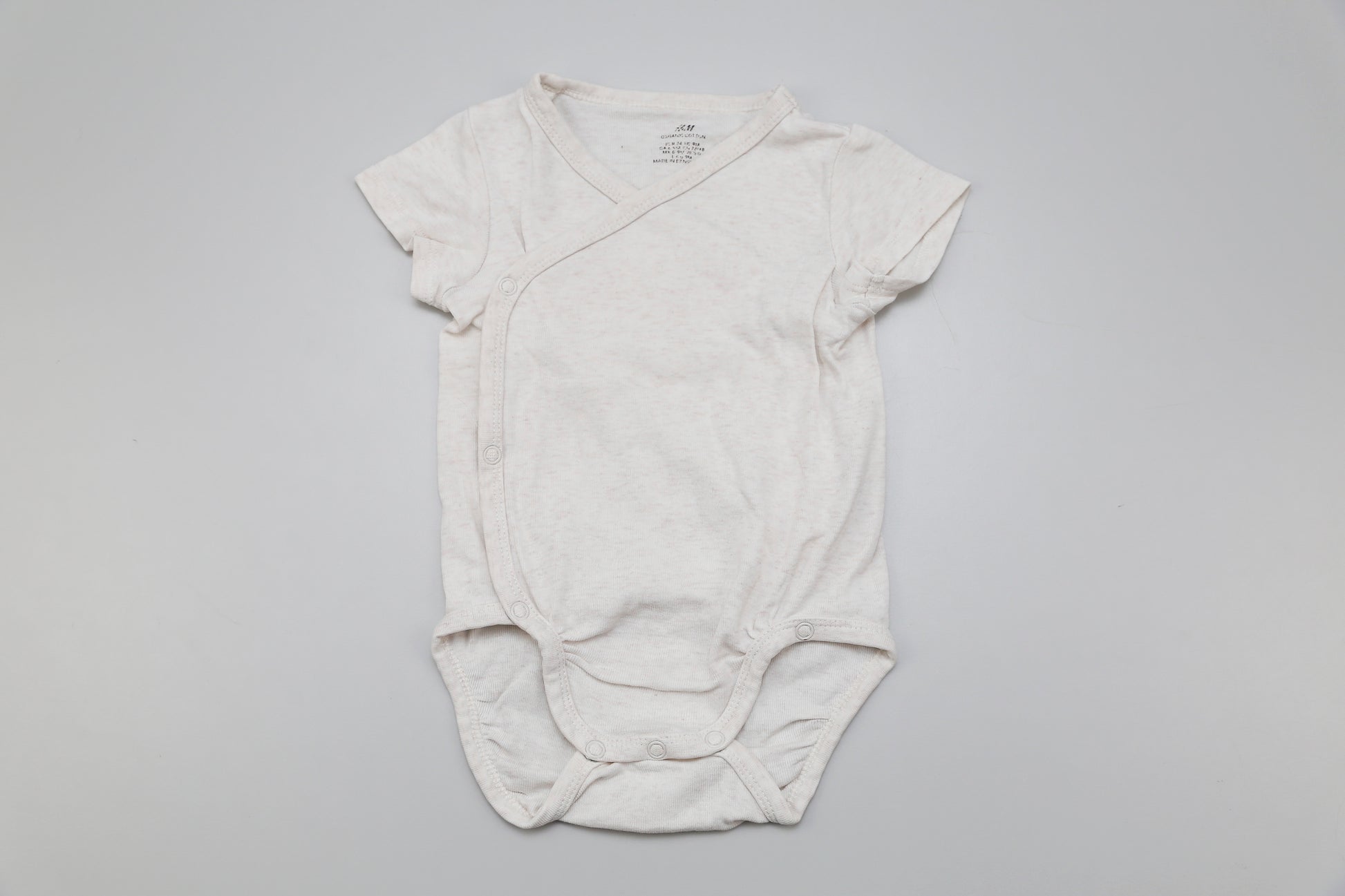 Zeitloser Wickelbody mit kurzen Ärmeln in neutralem Beige – aus 100% Bio-Baumwolle. Für Mädchen und Jungen geeignet. Größe 74, weich, bequem und nachhaltig.